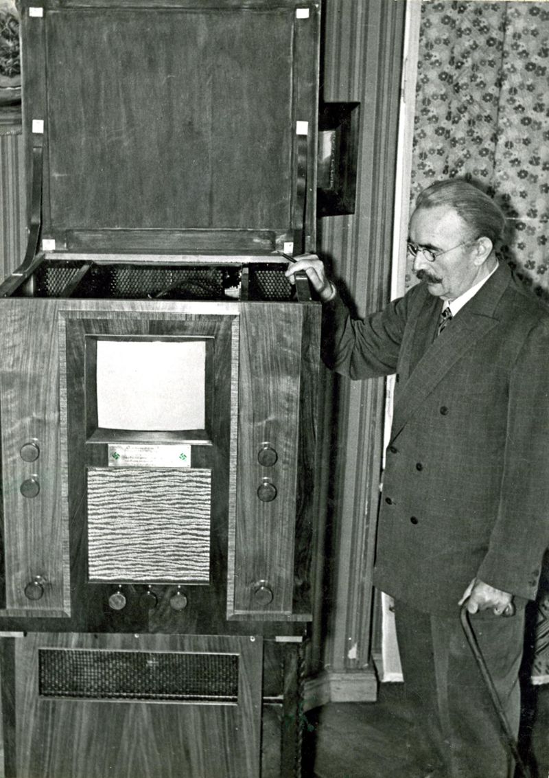 Fotografie Paul Nipkow mit dem Telefunken-Fernsehapparat Nr.13, den er zur Ernennung zum Ehrenpräsidenten der Reichsrundfunkkammer überreicht bekam, 2 Stück
