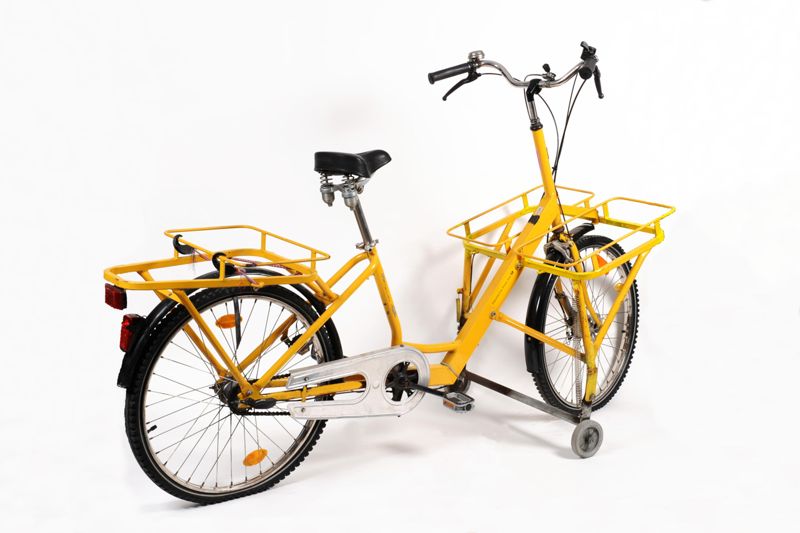 Fahrrad für Zusteller der Deutschen Post AG mit verlängertem Spezialrahmen, ausklappbaren Stützrädern und drei Gepäckträgern mit eingestellten Posttaschen